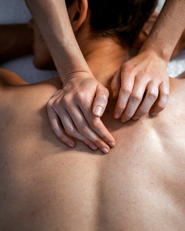 Physiotherapeut massiert verspannte rueckenmuskulatur